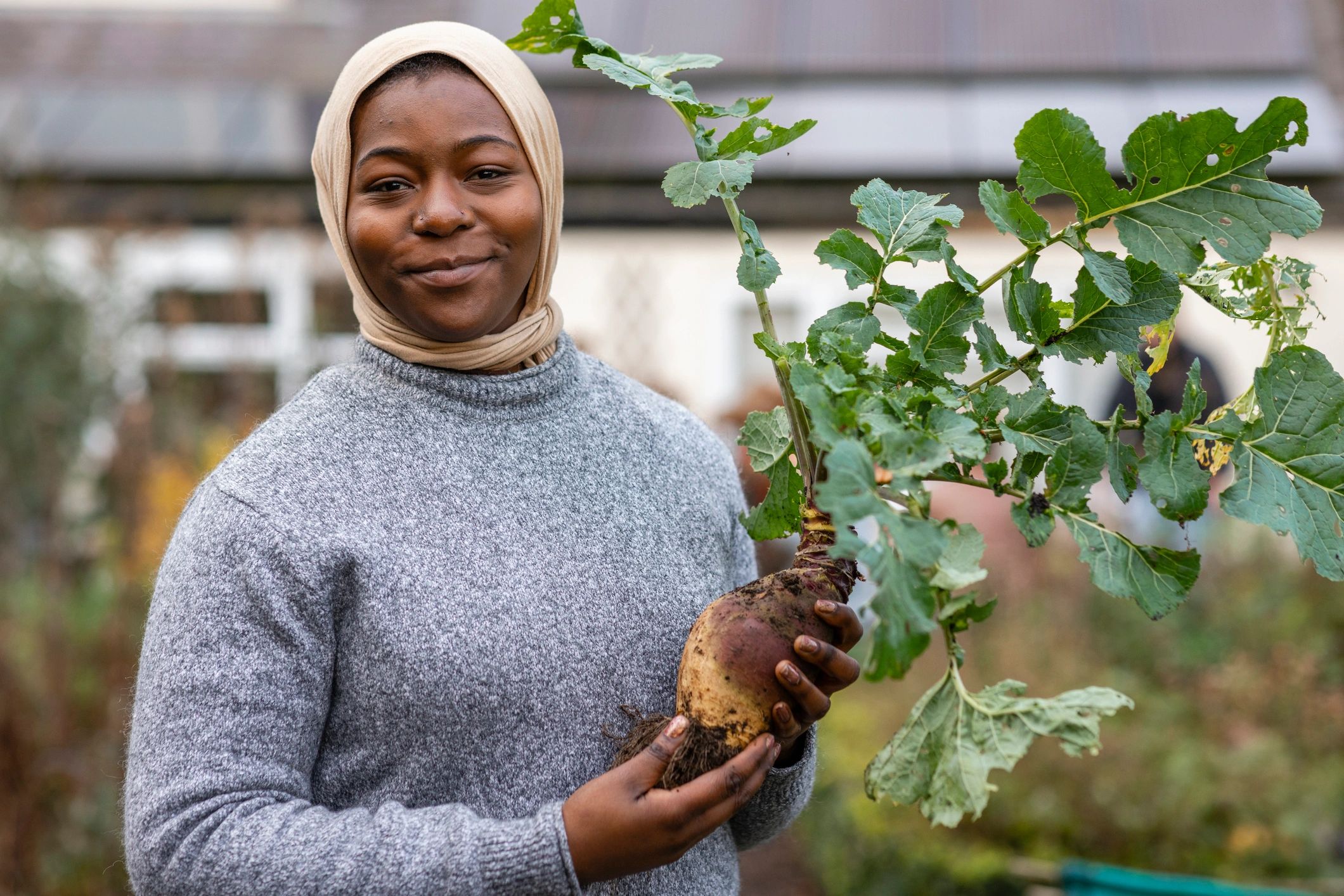 Farmer holding a freshly harvested root vegetable on a sustainable community farm